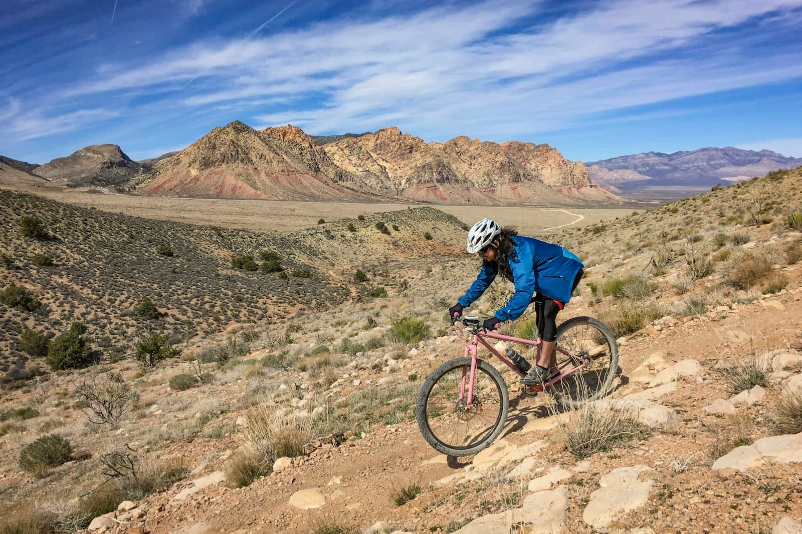 Une femme dévale en VTT une piste rocailleuse