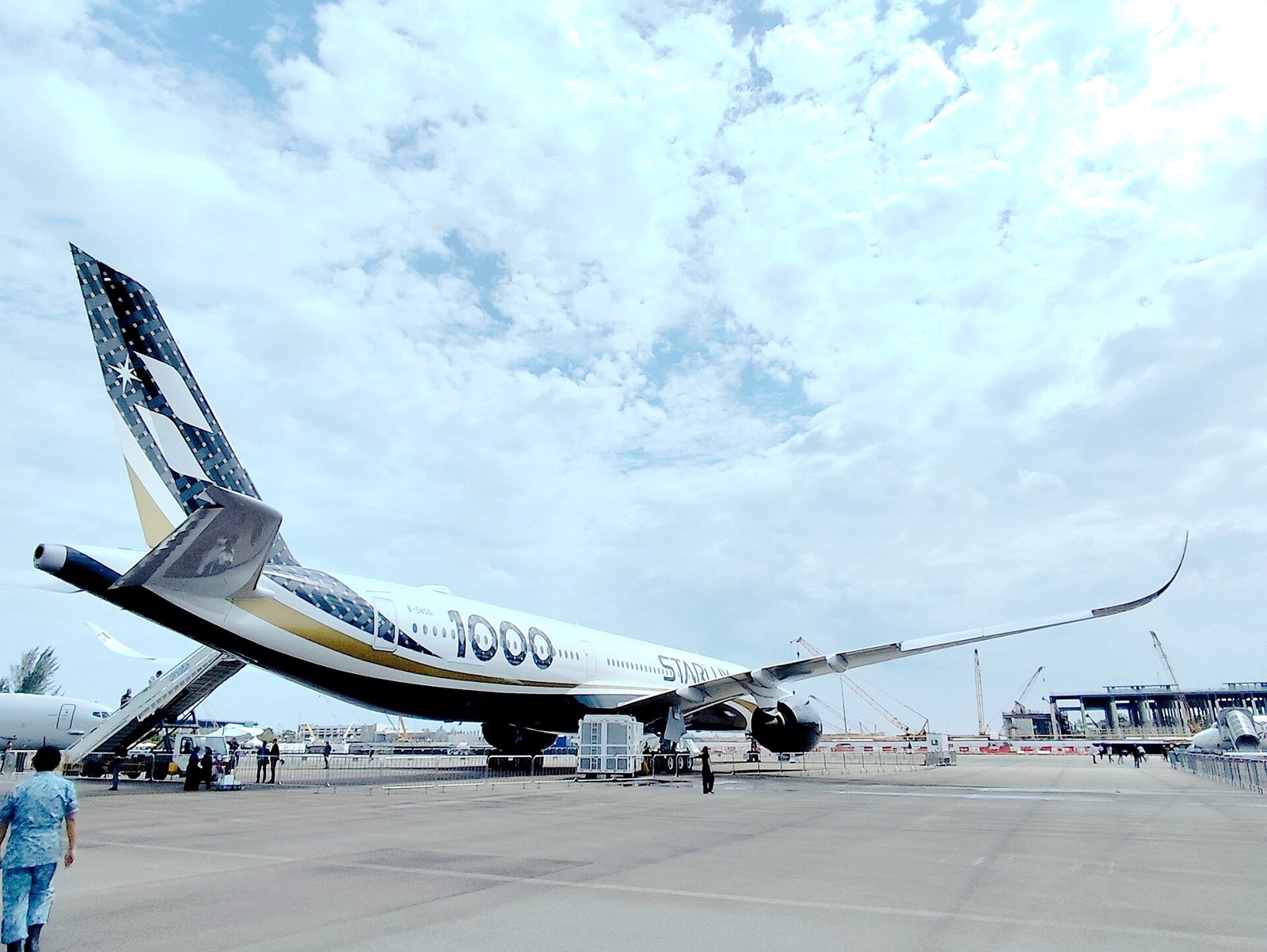 Un Airbus A350-1000 de démonstration, dérive noire et blanche marquée 1000, exposé sur le tarmac d’un salon aéronautique sous un ciel nuageux
