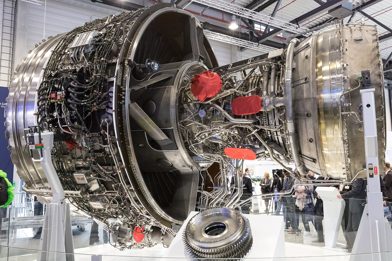 Un moteur Rolls-Royce Trent XWB exposé sans capot, avec ses faisceaux de câbles et sa soufflante, dans un hall de salon