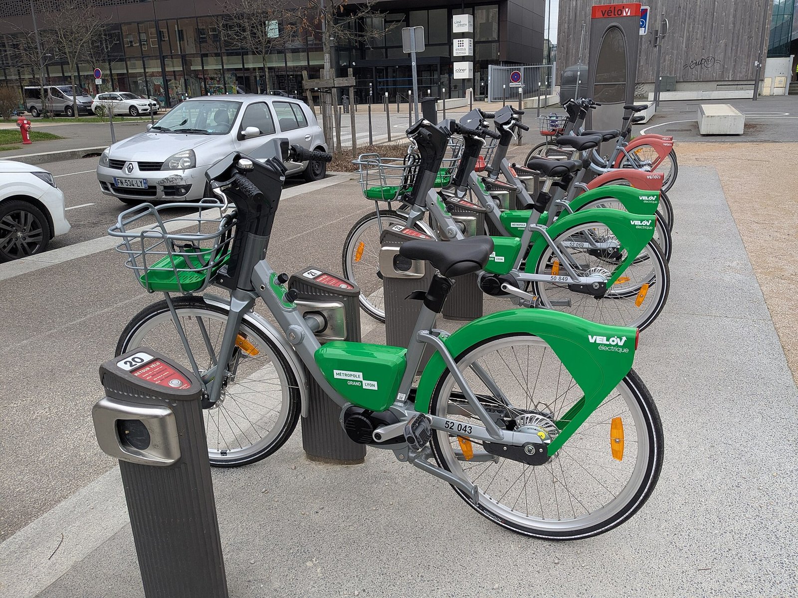 Rangée de vélos électriques en libre-service verts et gris à une station, dans une rue de Lyon