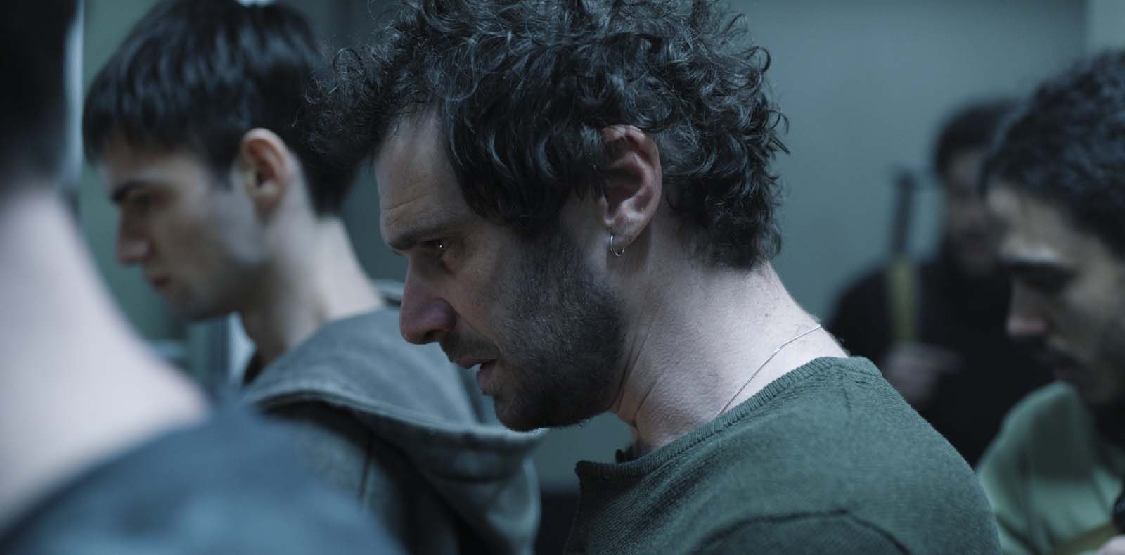 Des otages serrés dans un couloir sombre, visages tendus, dans une scène de la série Des vivants