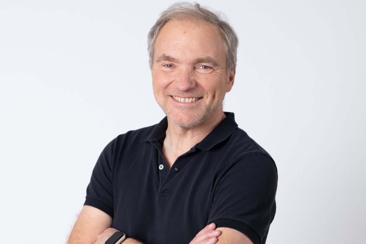 Portrait souriant de Patrick Maurice, bras croisés, en polo sombre sur fond blanc