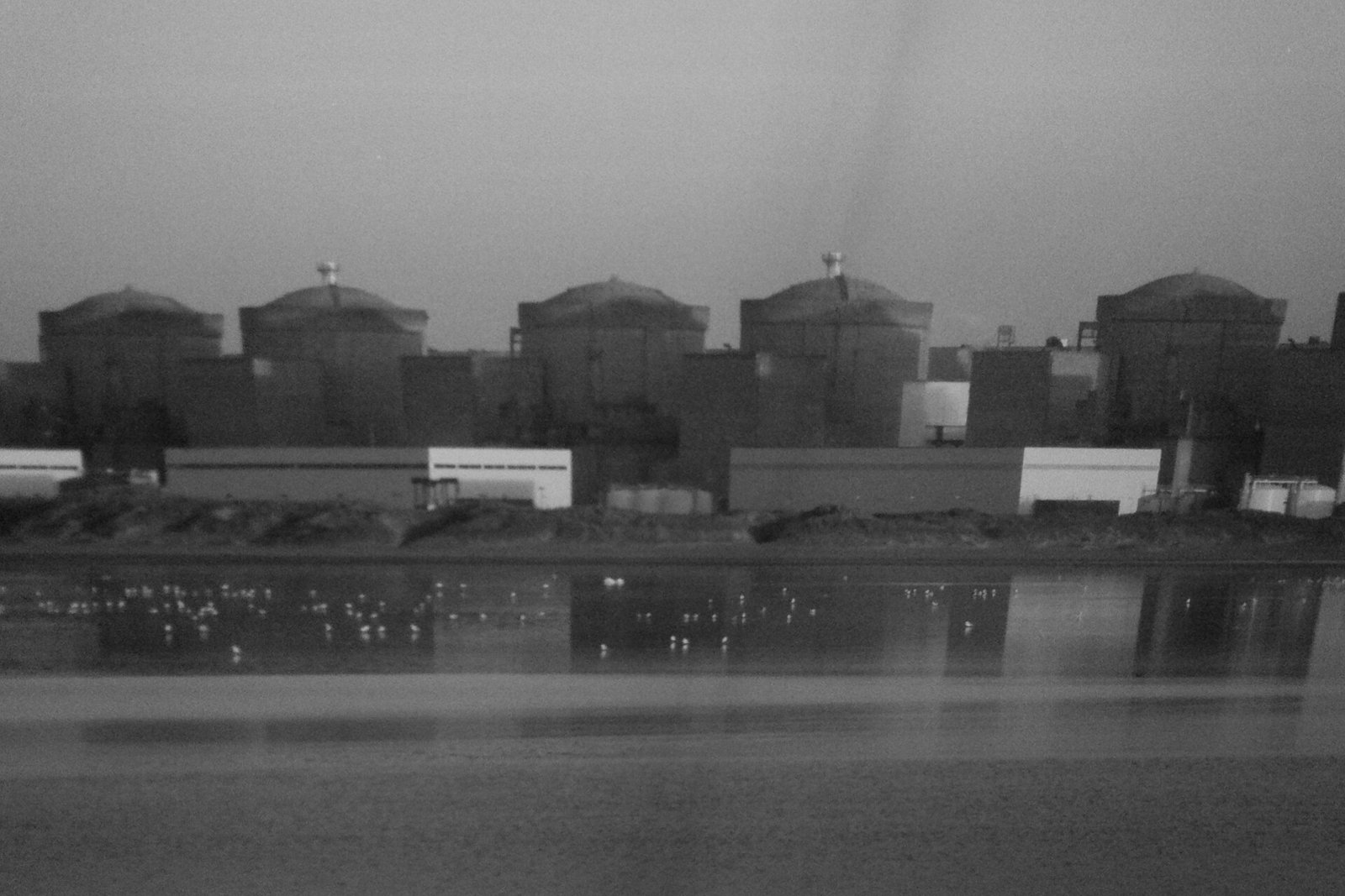 Les six bâtiments réacteurs de la centrale de Gravelines alignés au bord de l’eau, en noir et blanc