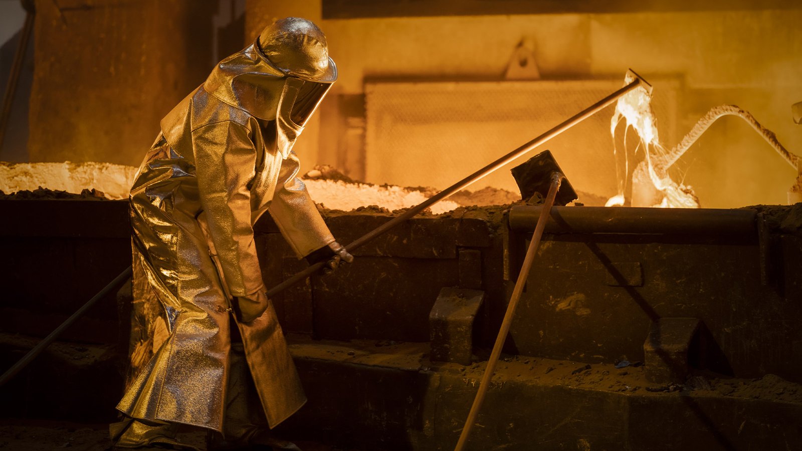 Un opérateur en tenue de protection lors d’une coulée de métal en fusion dans une usine d’alliages