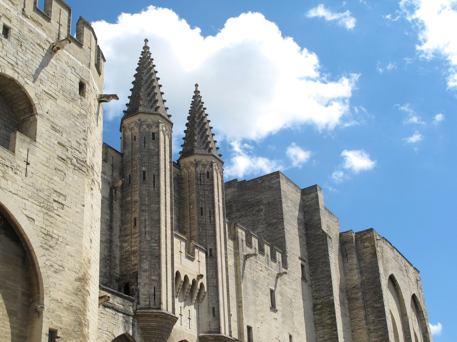Les tours gothiques du Palais des Papes d’Avignon sous un ciel bleu traversé de nuages