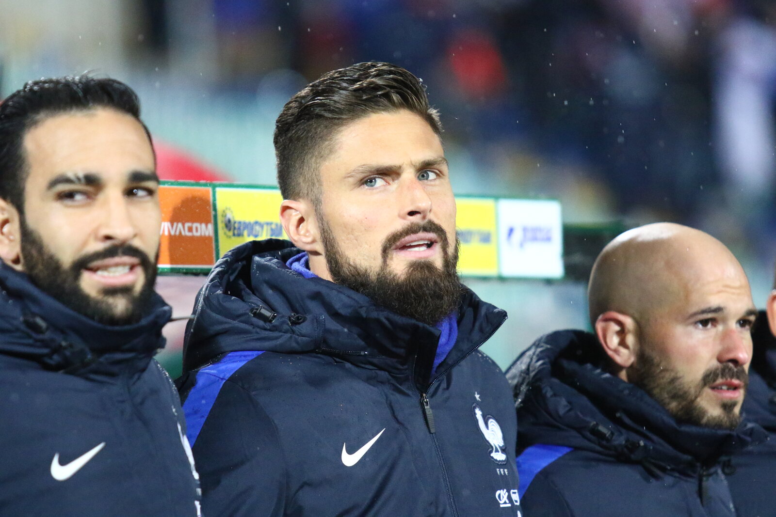 Olivier Giroud, barbe et doudoune de l’équipe de France, regard concentré sur le banc des remplaçants