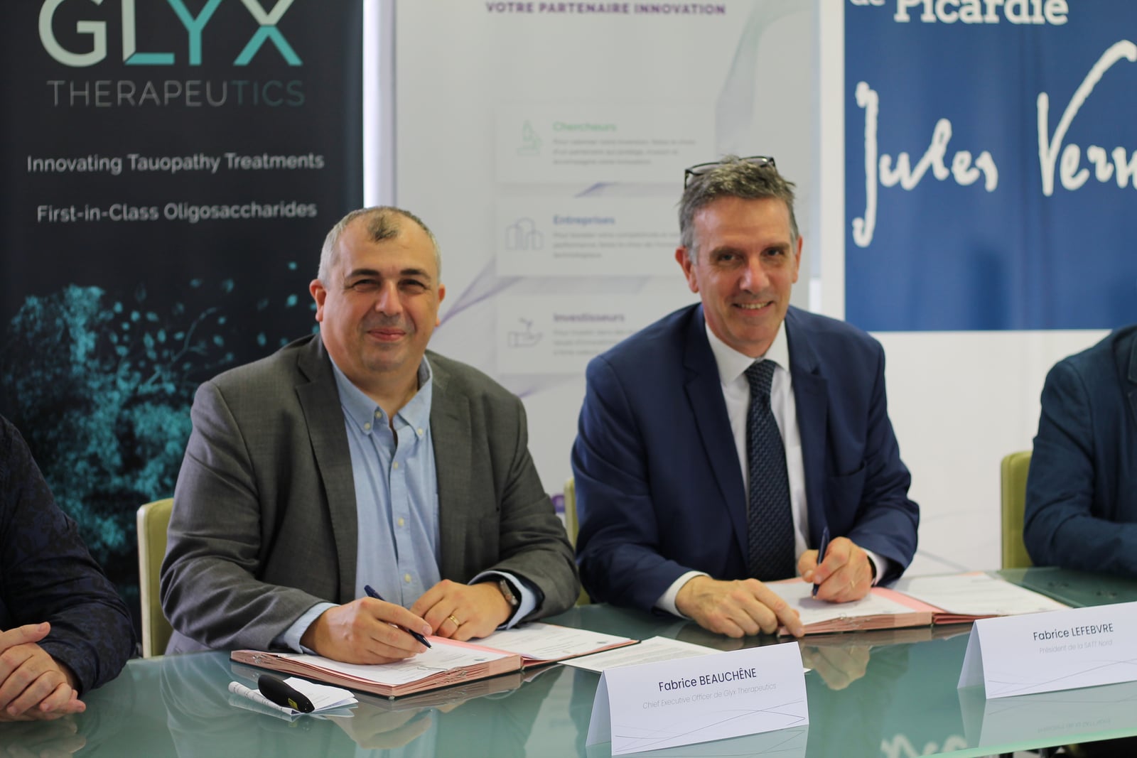 Fabrice Beauchêne et Fabrice Lefebvre souriants, stylos en main, devant les dossiers de licence Glyx Therapeutics et SATT Nord