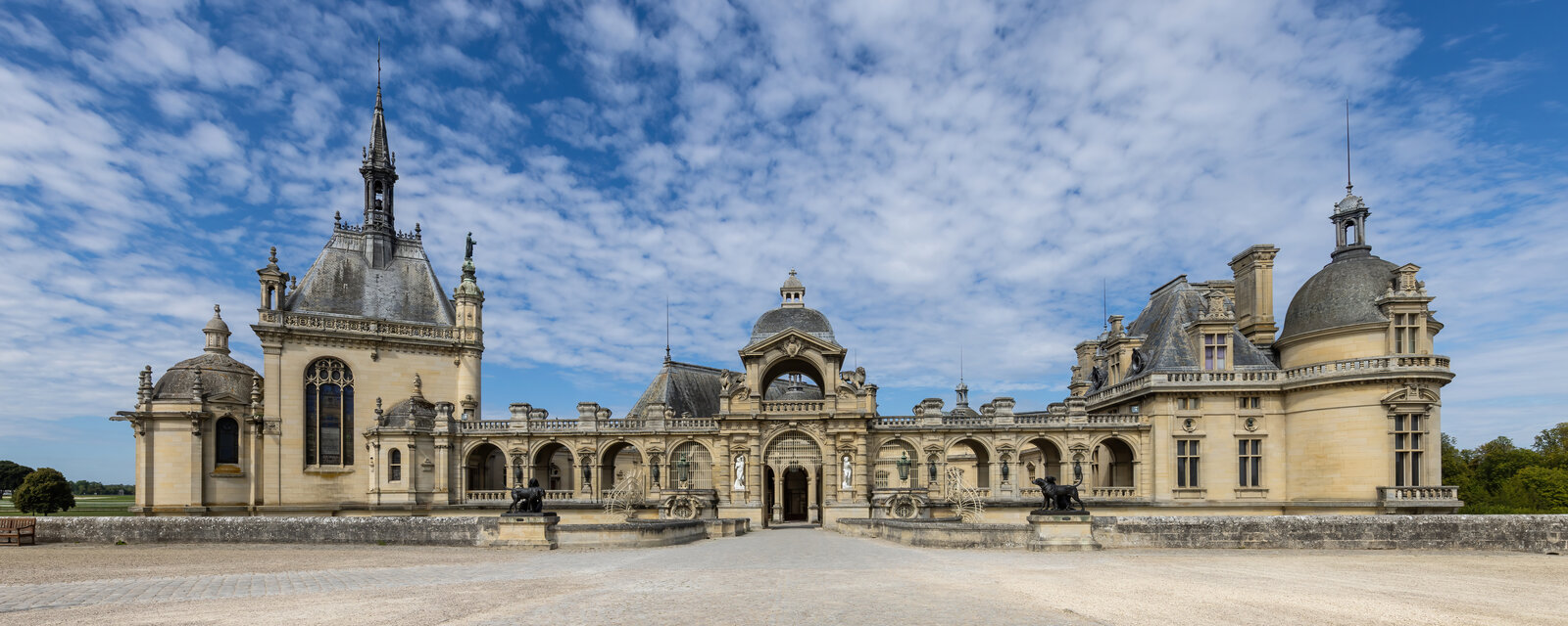 Façade principale du château de Chantilly sous un ciel bleu, tourelles et toits d’ardoise