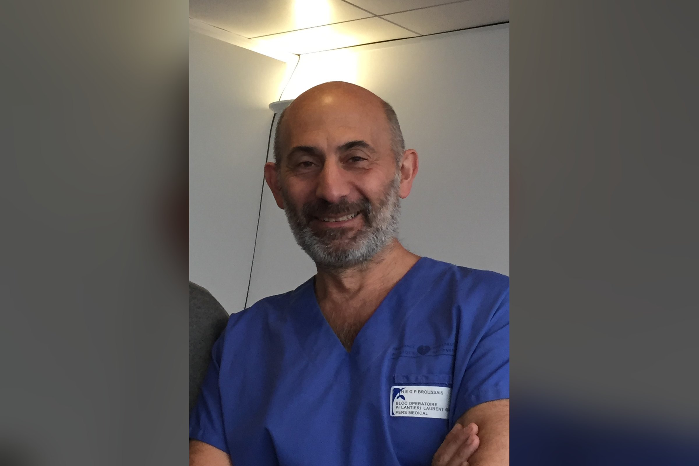 Le Pr Laurent Lantieri, souriant, en tenue de bloc bleue, bras croisés
