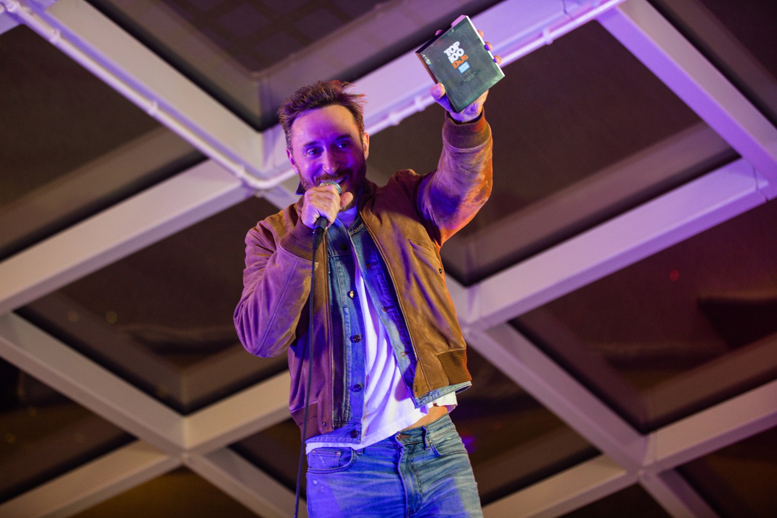 David Guetta, micro en main et sourire aux lèvres, brandit le trophée du Top 100 DJs sur scène