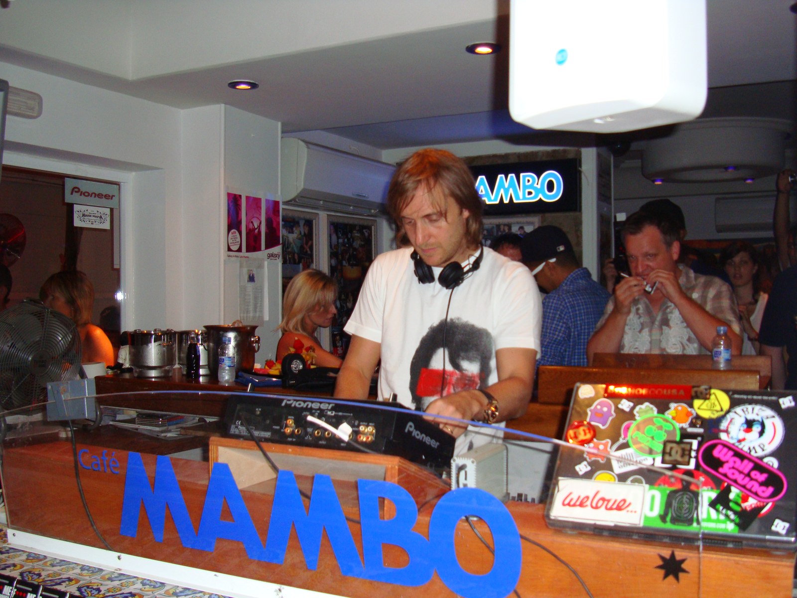 David Guetta, casque autour du cou, aux platines du Café Mambo à Ibiza, entouré de quelques clubbers