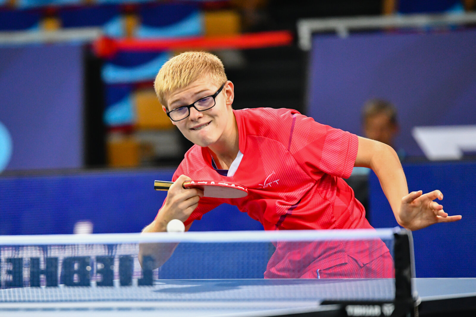 Félix Lebrun, lunettes et maillot rouge, raquette en prise stylo, prêt à frapper