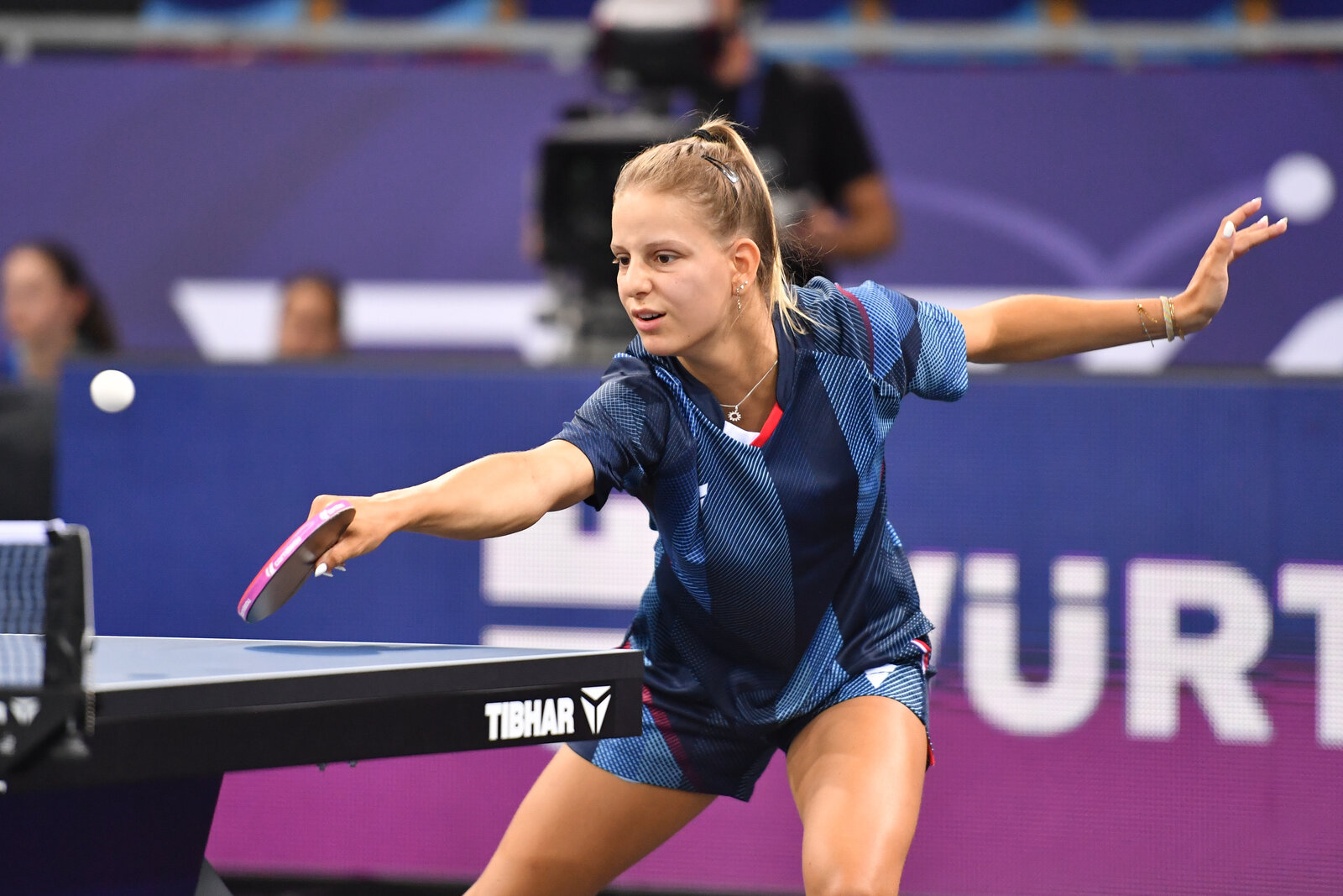 Charlotte Lutz, cheveux en queue de cheval, en pleine frappe de revers au-dessus de la table