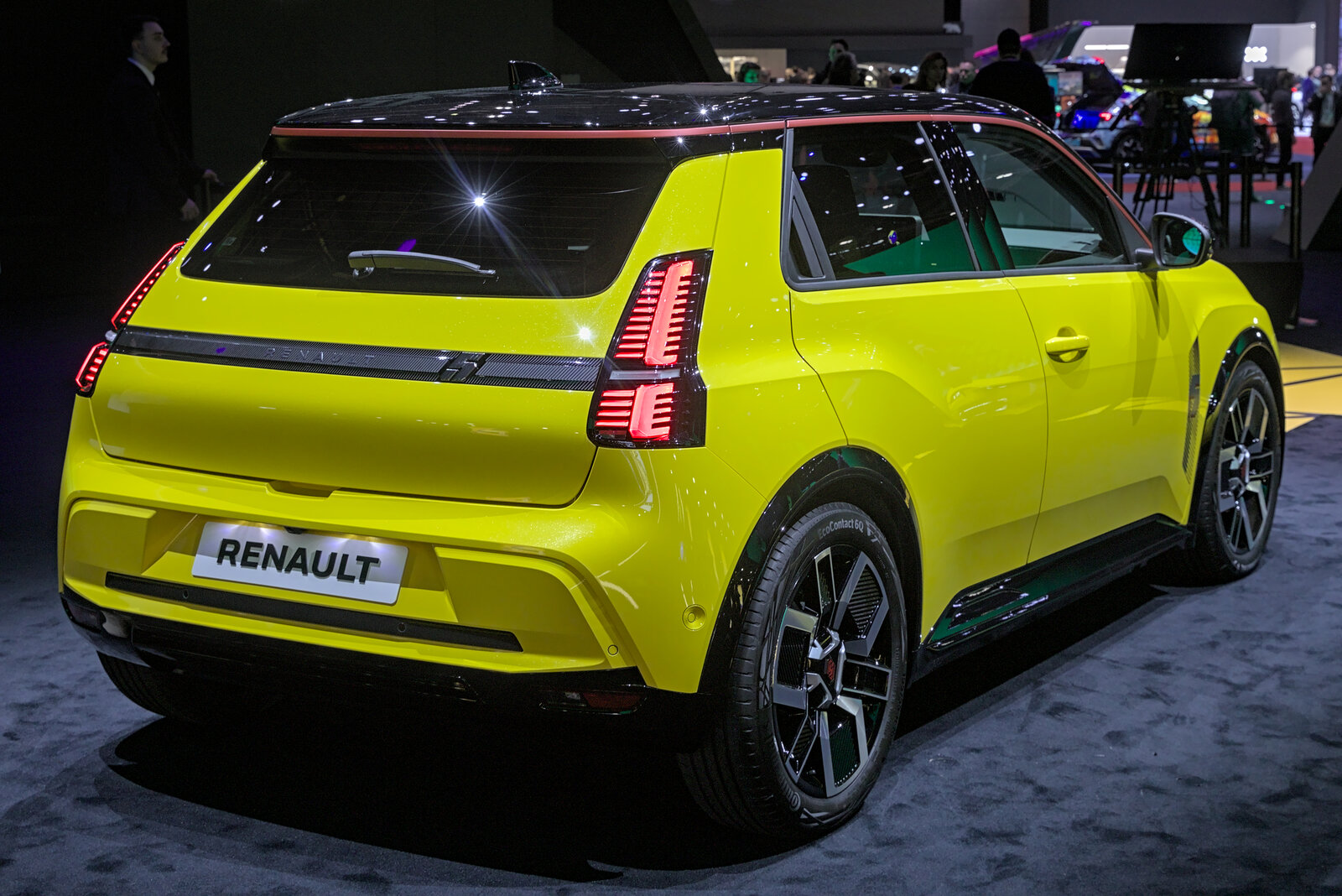 Renault 5 E-Tech électrique jaune et noire exposée sur un stand, trois quarts avant