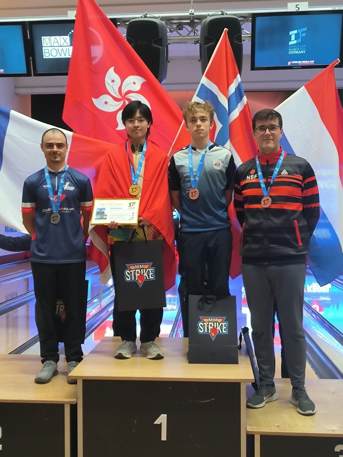 Grégory Rius, médaille d’argent au cou, sur le podium de la Coupe du monde à côté du vainqueur Jovi Ma, drapeau de Hong Kong sur les épaules