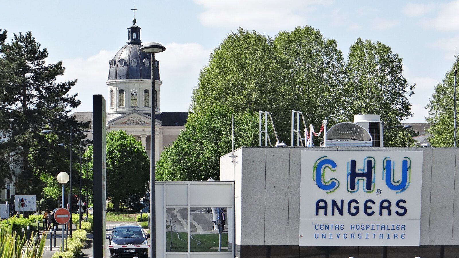 L’entrée du CHU d’Angers avec son enseigne bleue et blanche, devant un dôme et des arbres