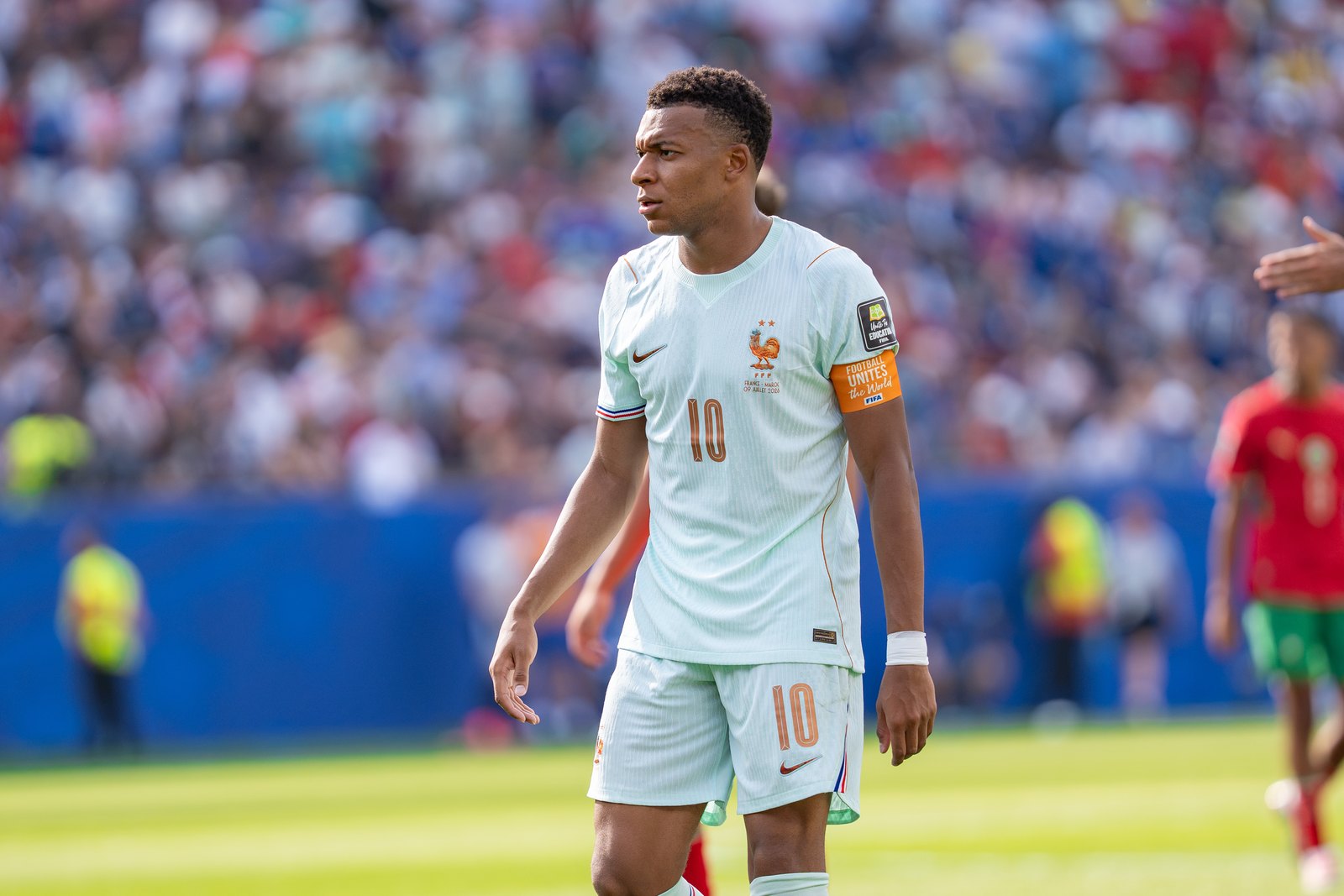 Kylian Mbappé, brassard de capitaine au bras, en maillot blanc de l’équipe de France
