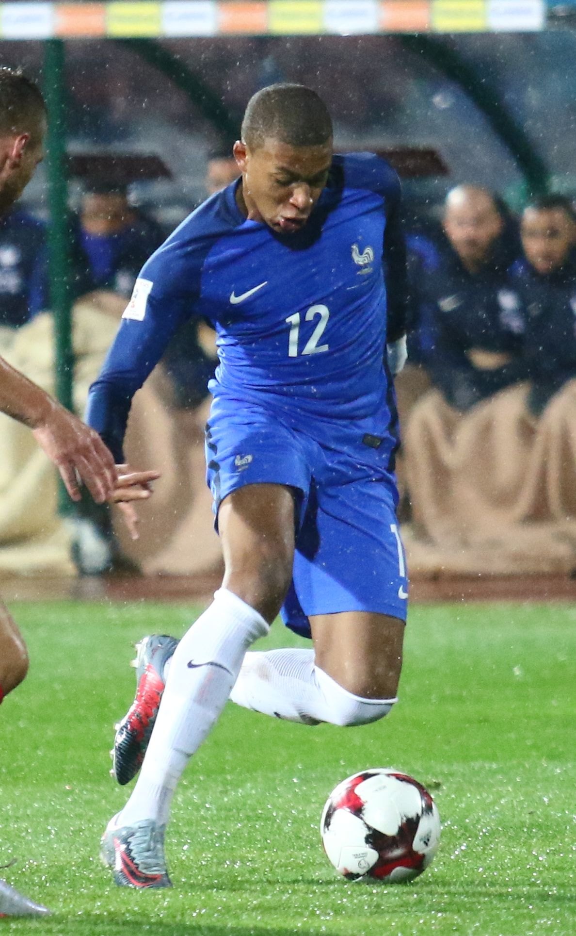 Le jeune Kylian Mbappé, numéro 12 de l’équipe de France, conduit le ballon sous la pluie
