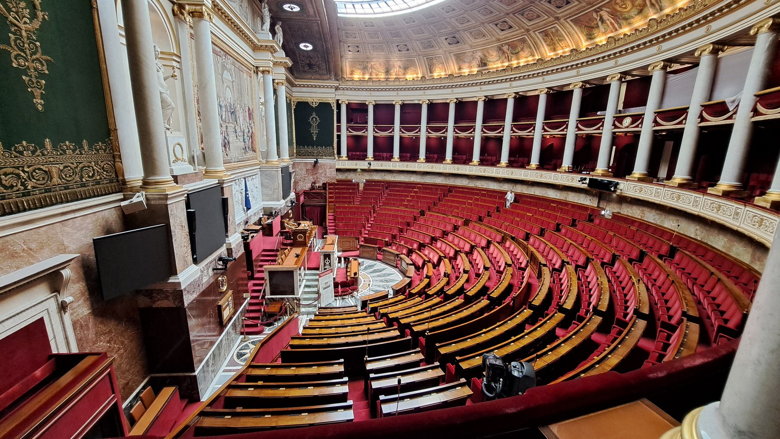 L’hémicycle de l’Assemblée nationale vu des tribunes, avec ses rangées de sièges rouges en arc de cercle et sa colonnade