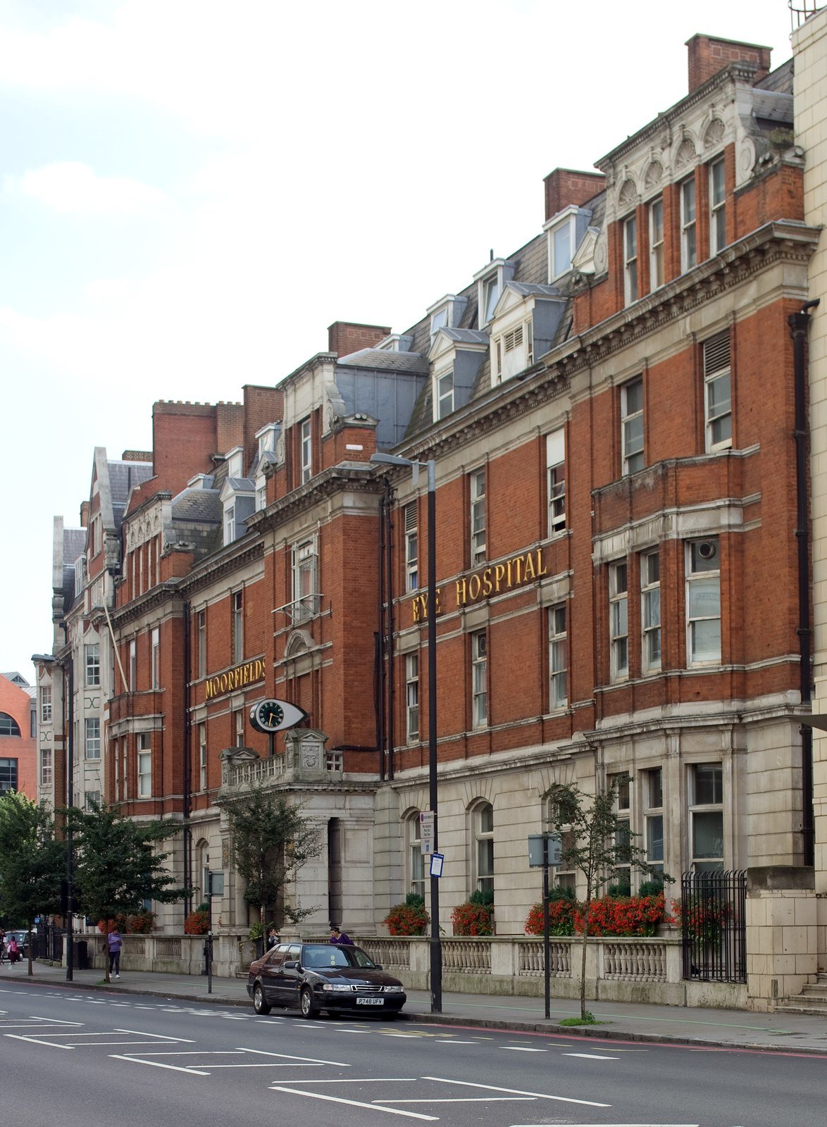 Façade de briques rouges de l’hôpital Moorfields sur City Road à Londres, avec une rue et des voitures garées