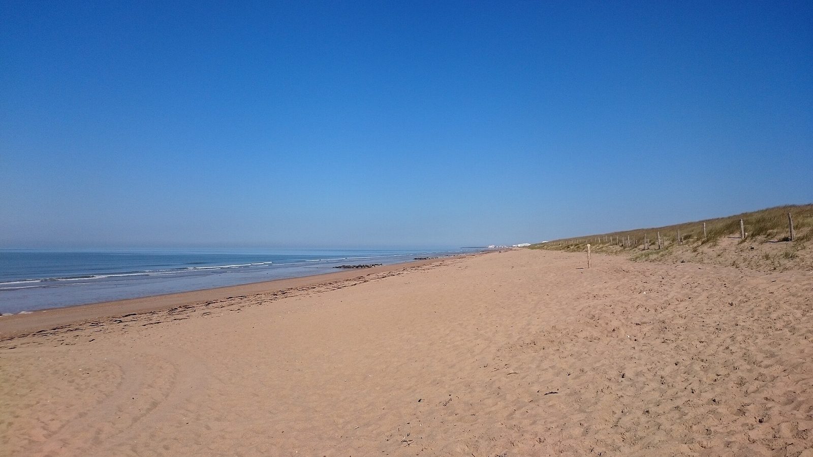 Longue plage de sable de Sion, à Saint-Hilaire-de-Riez, sous un ciel bleu