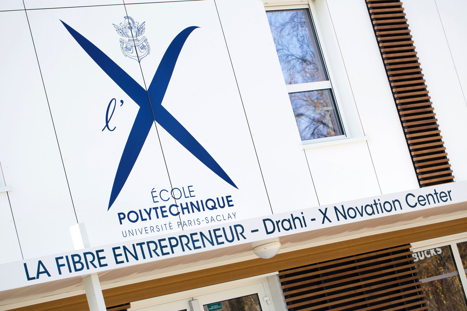 Façade du bâtiment La Fibre Entrepreneur – Drahi X-Novation Center, avec le grand X bleu de l’École polytechnique