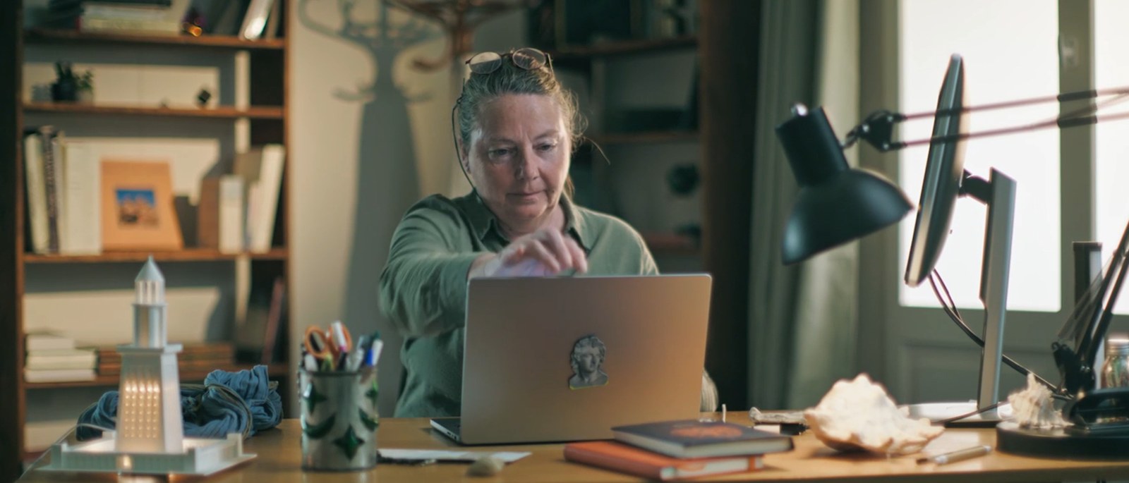 Isabelle Hairy du CNRS devant son ordinateur, une maquette de phare sur le bureau