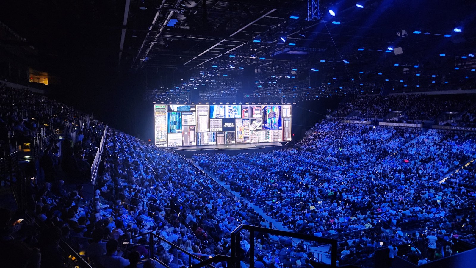 Une salle comble plongée dans la lumière bleue face à l’écran géant d’une keynote Nvidia