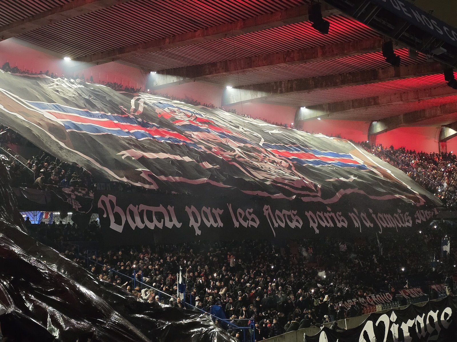 Tifo géant des ultras parisiens au Parc des Princes, banderole Fluctuat nec mergitur sous un éclairage rouge