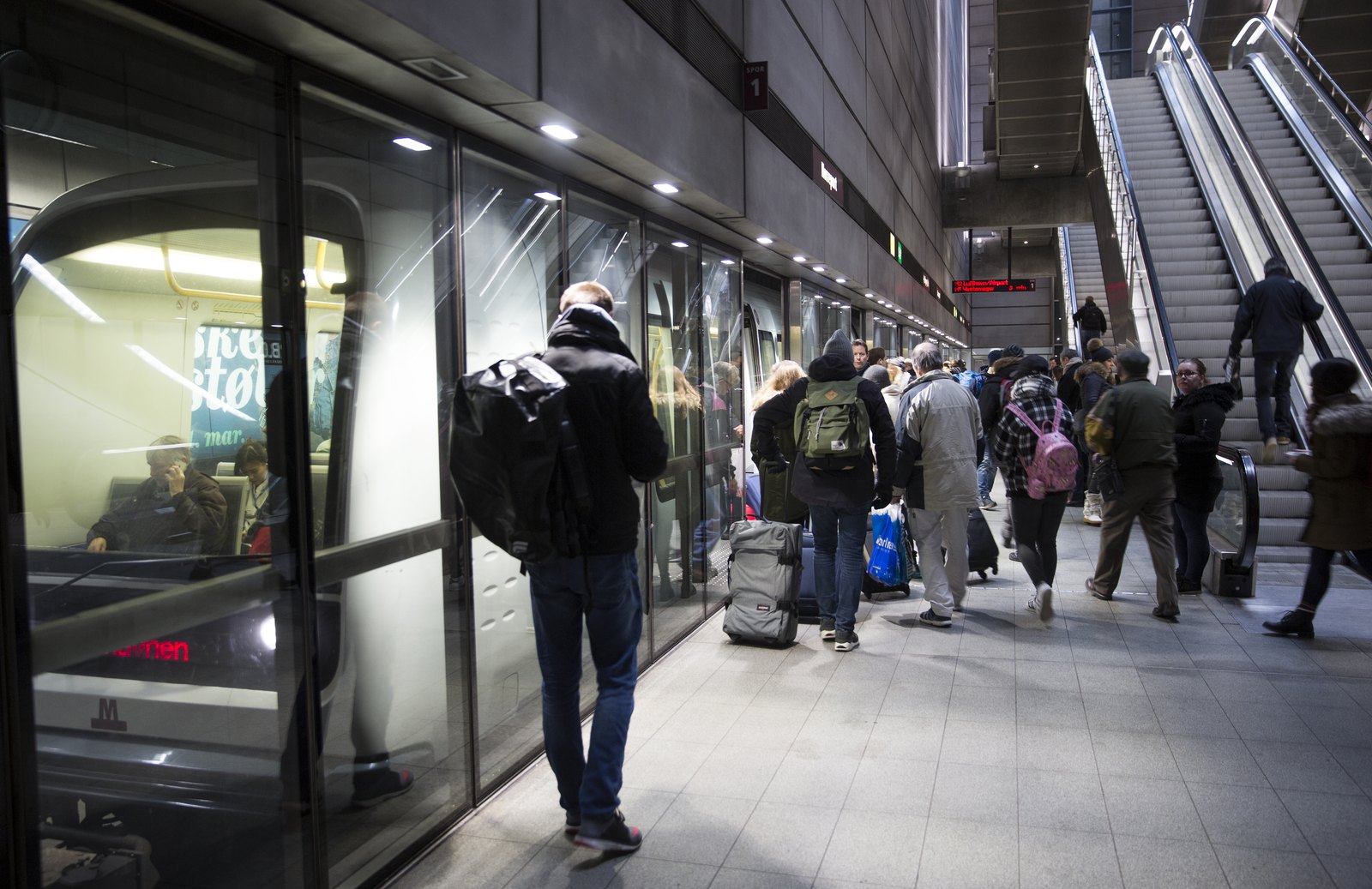 Voyageurs avec sacs et valises dans le couloir de la station Nørreport, près des escaliers mécaniques