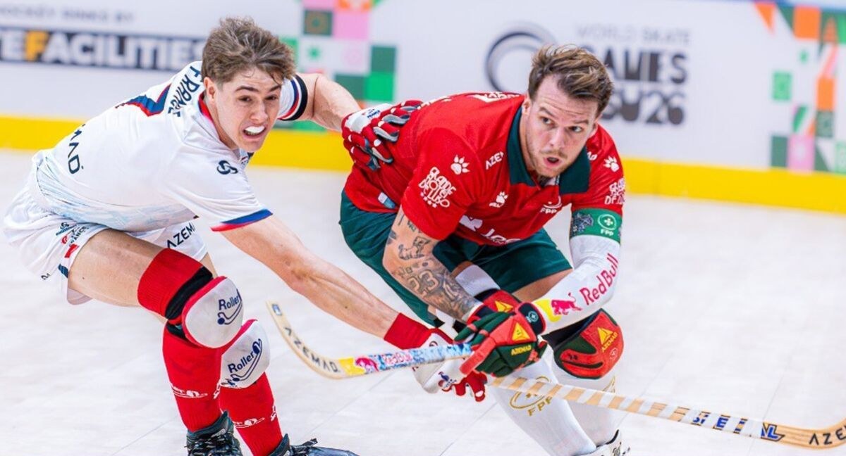 Un joueur français en maillot blanc, bouche ouverte sous l’effort, plonge crosse en avant face à un Portugais en maillot rouge