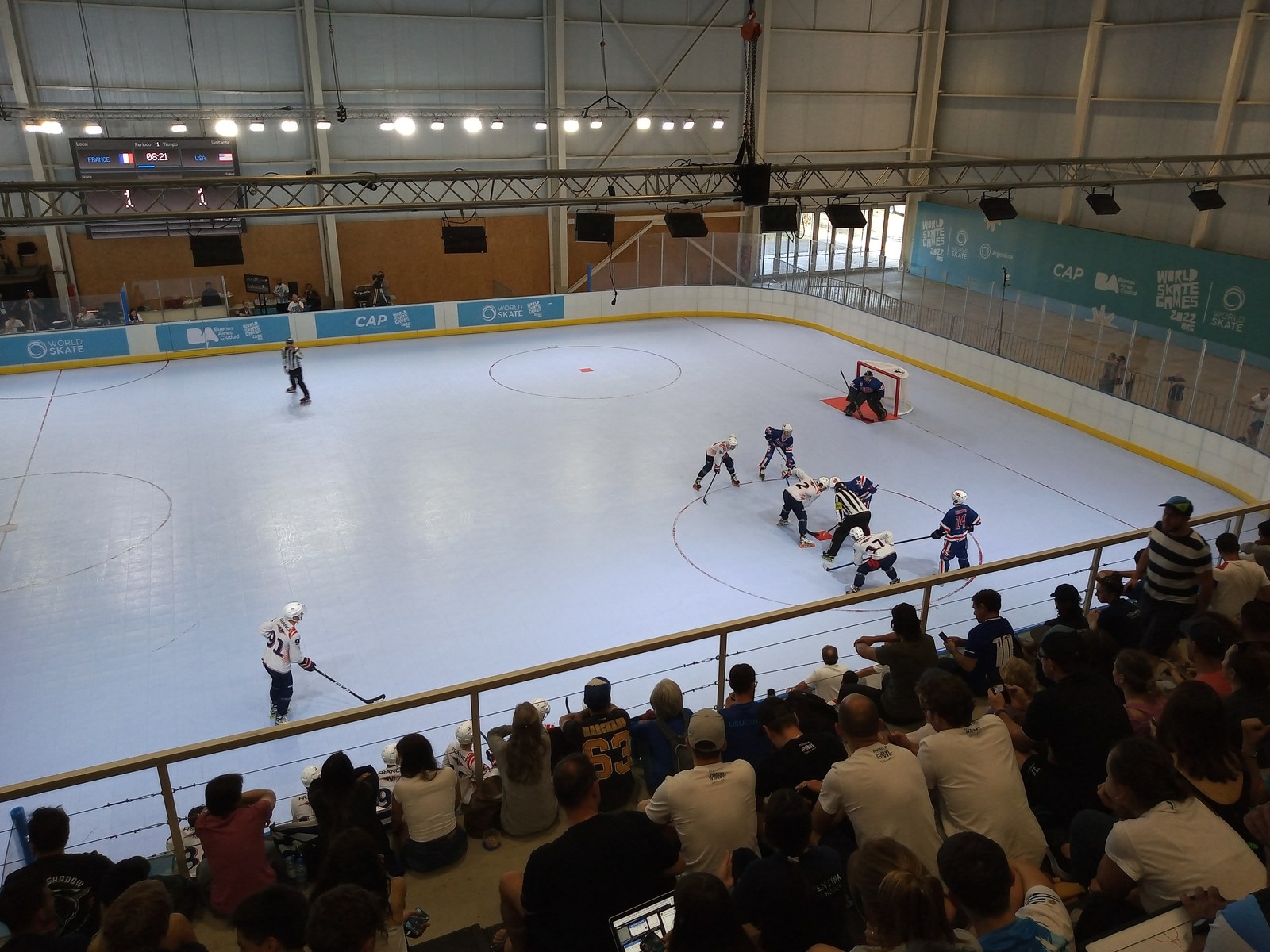 Match de roller hockey France–États-Unis, joueurs en action autour d’une mise au jeu sur une piste bleue