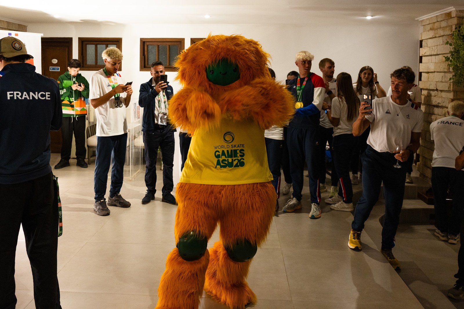 Athlètes français autour de la mascotte orange des World Skate Games ASU26, certains portant des médailles
