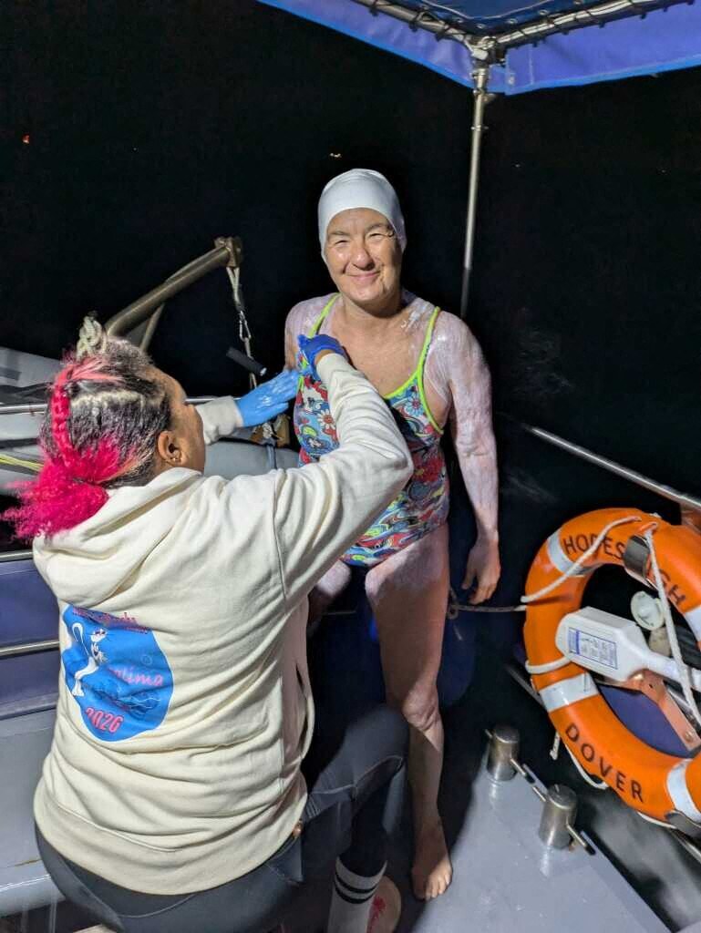 Salima Bouayad Agha en maillot et bonnet sur le pont du bateau, pendant qu’une accompagnatrice la prépare