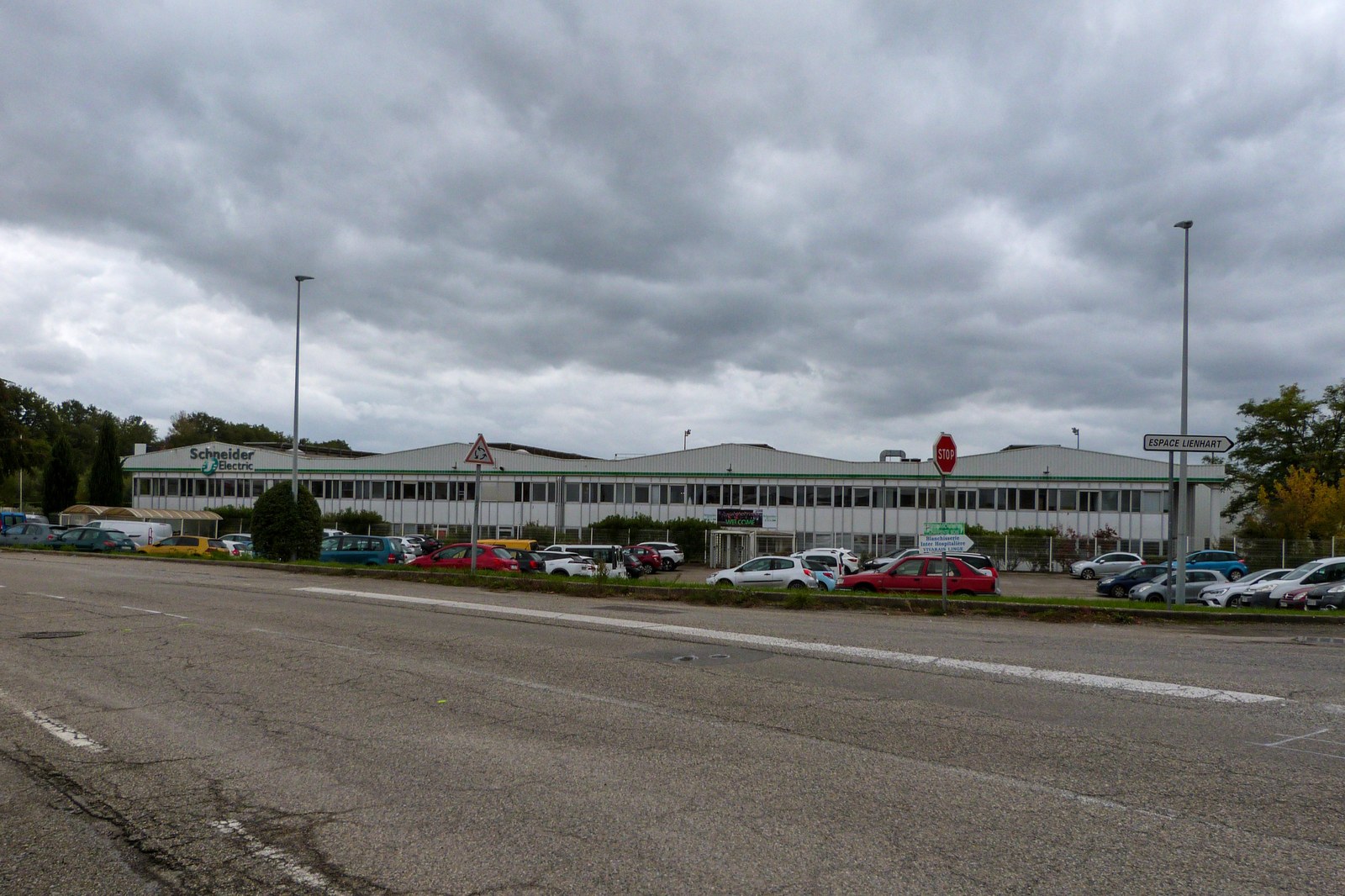 Usine Schneider Electric à Aubenas, en Ardèche, sous un ciel couvert, avec parking plein