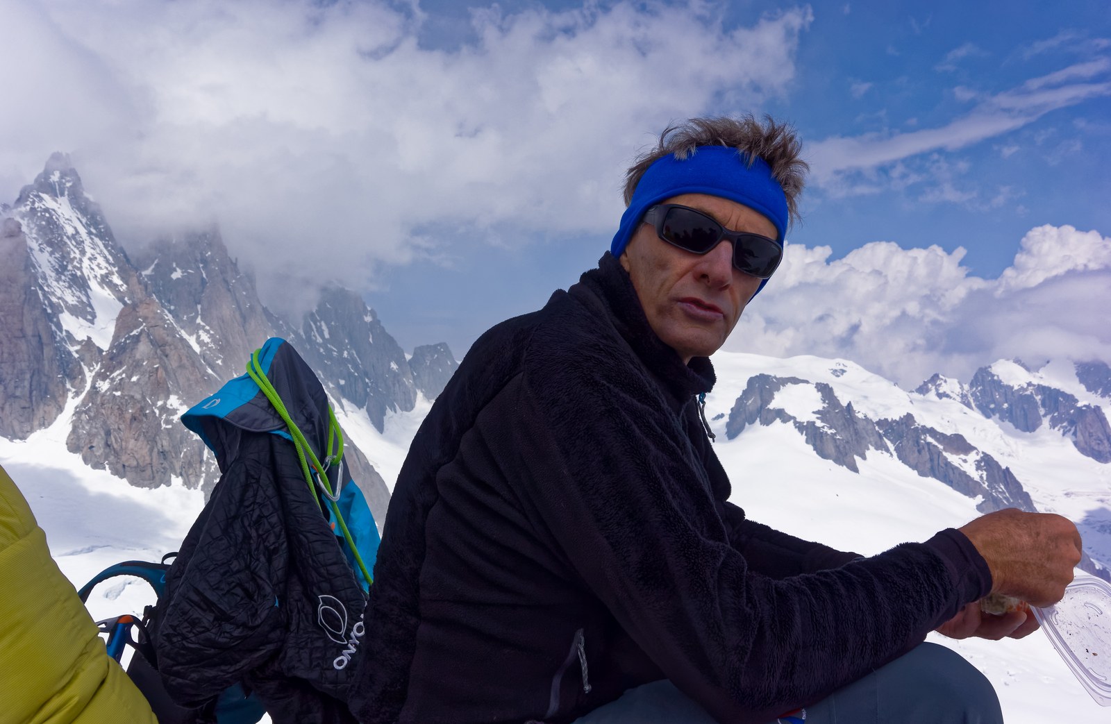 L’alpiniste François Marsigny assis au sommet de l’aiguille de Toule, face aux sommets enneigés du massif du Mont-Blanc