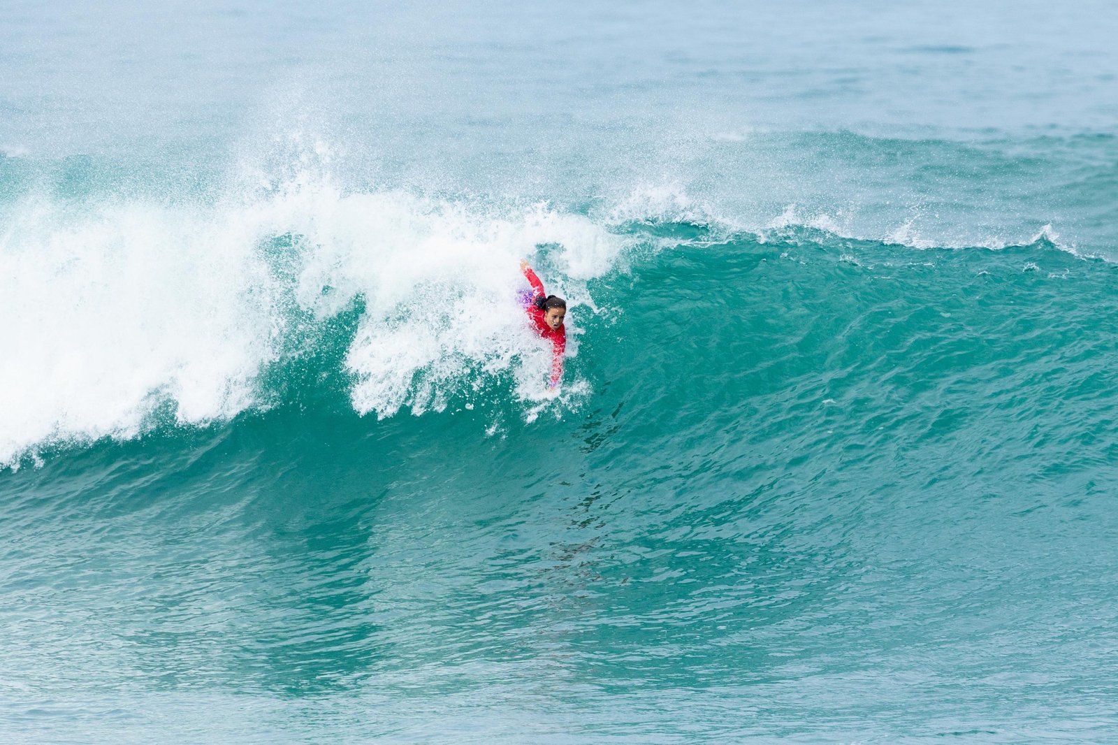 Une bodysurfeuse glisse dans le creux d’une vague turquoise qui déferle à Anglet