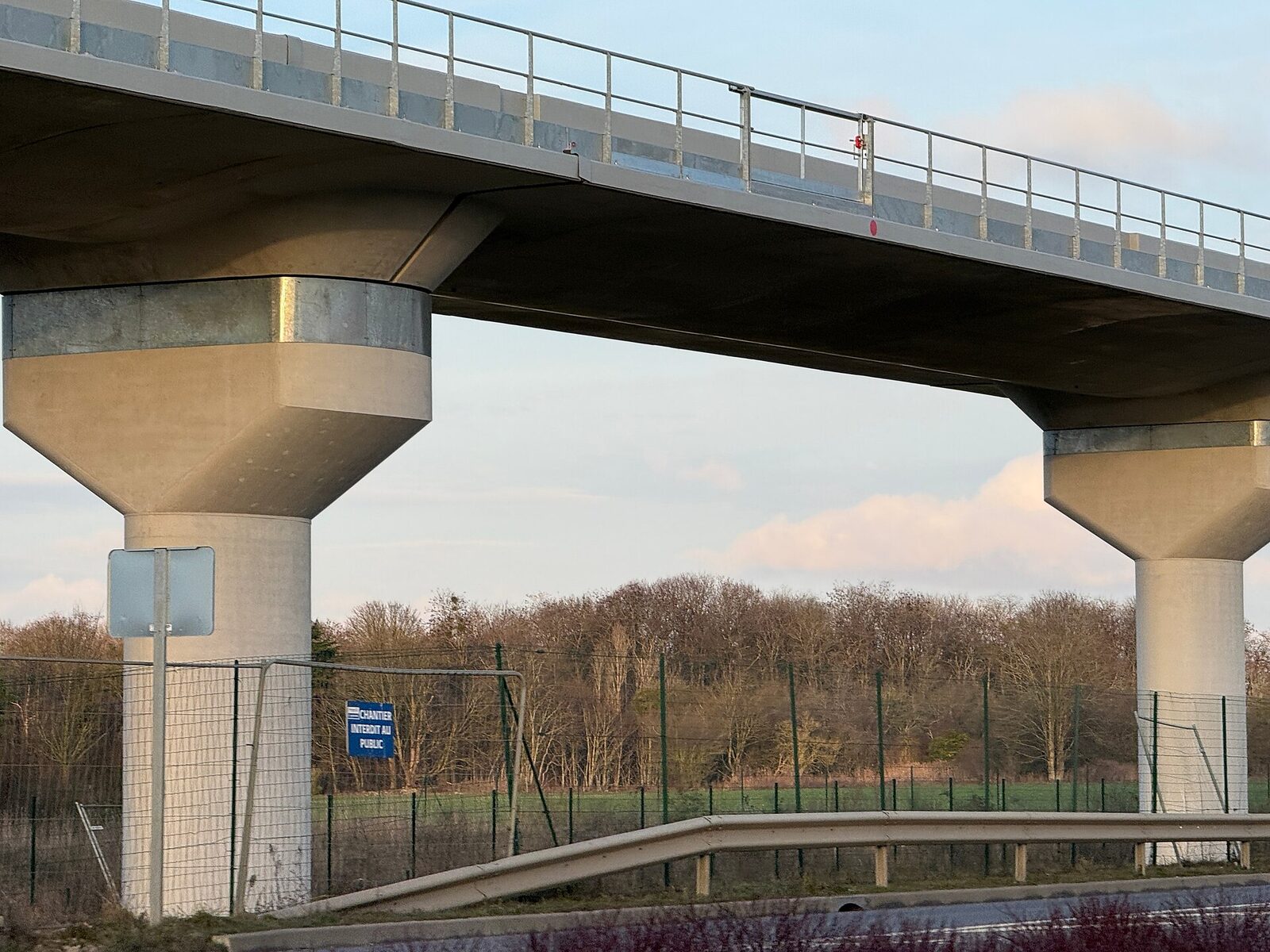 Vue en contre-plongée du tablier du viaduc posé sur des piles évasées, au-dessus d’une route