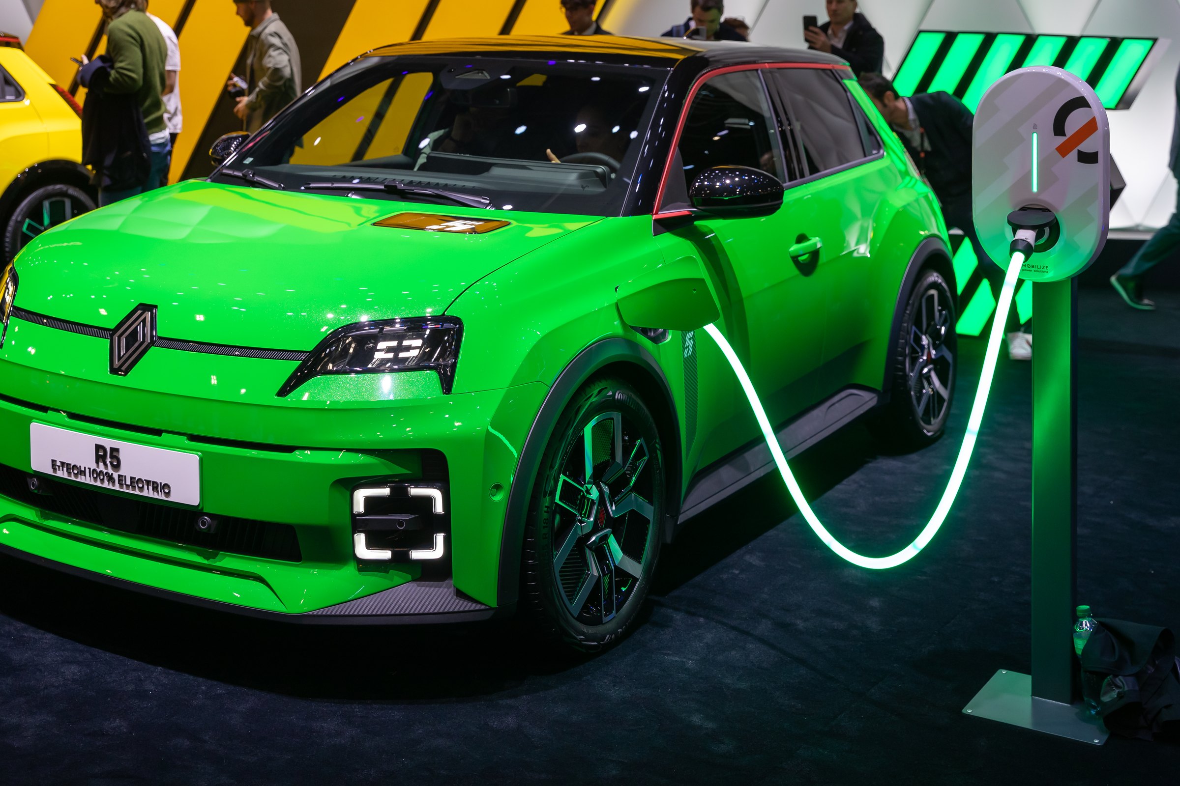 Une Renault 5 E-Tech électrique verte branchée à sa borne de recharge