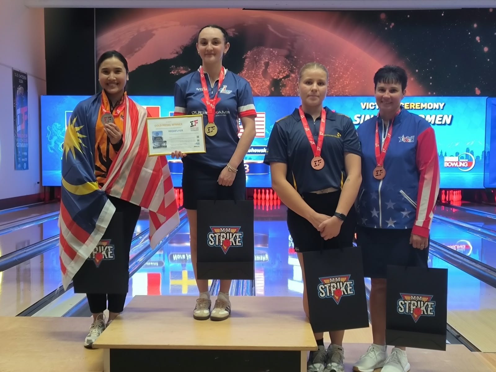 Manon Clément, médaille d’or au cou, sur la plus haute marche du podium de la Coupe du monde de Munich, entourée de Natasha Roslan, Nora Johansson et Shannon Pluhowsky