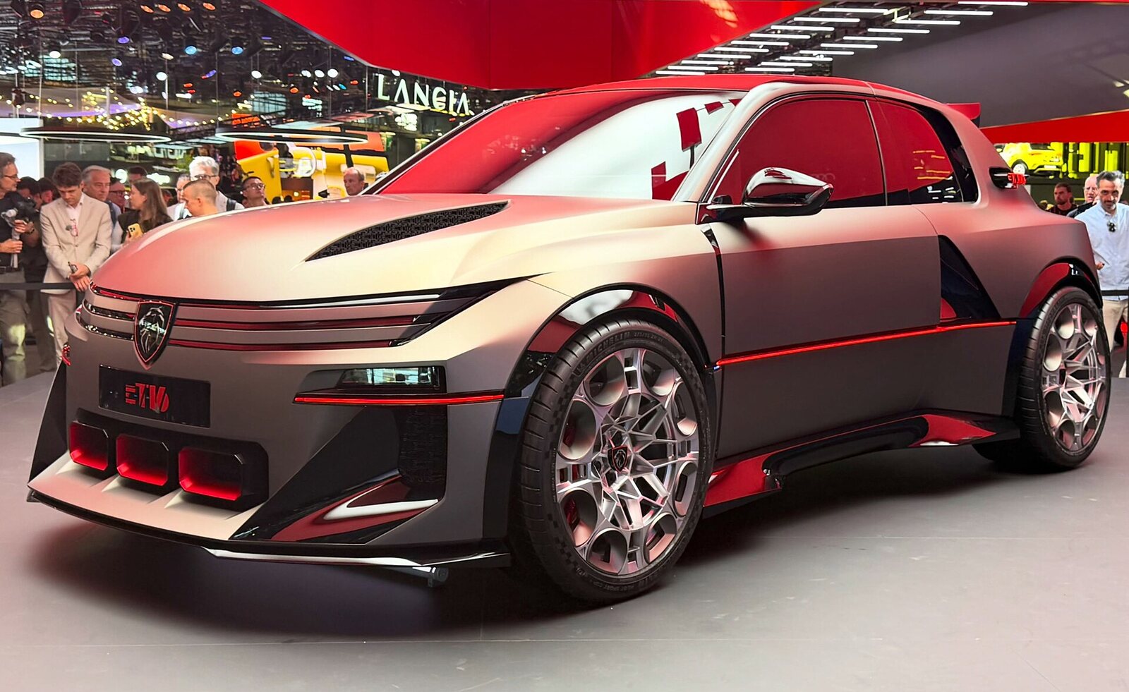 Le concept Peugeot E-T16 gris mat, liseré rouge et grosses jantes, vu de trois quarts avant sur le stand du Mondial de Paris